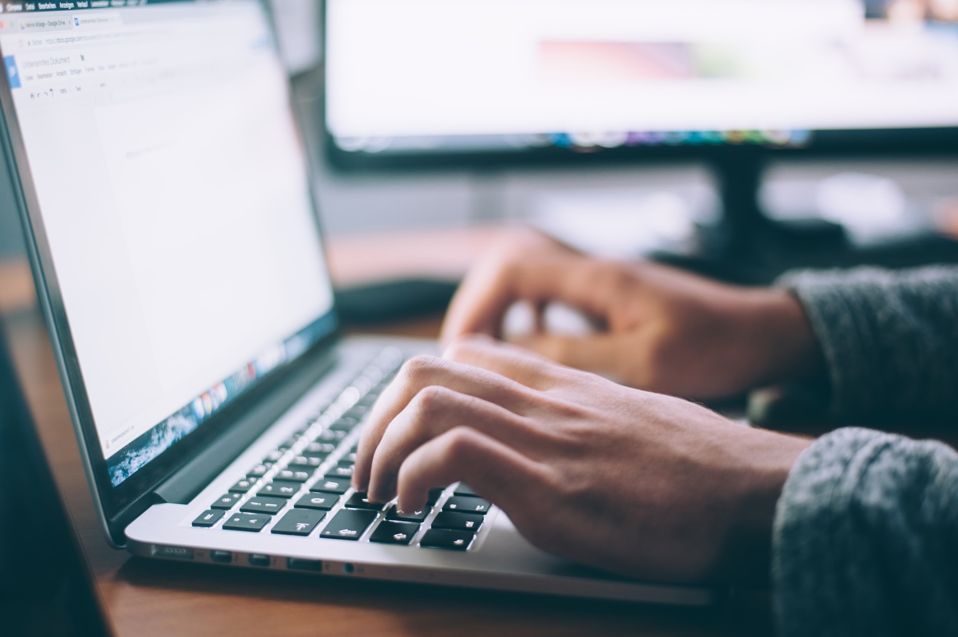 person's hand typing on a laptop